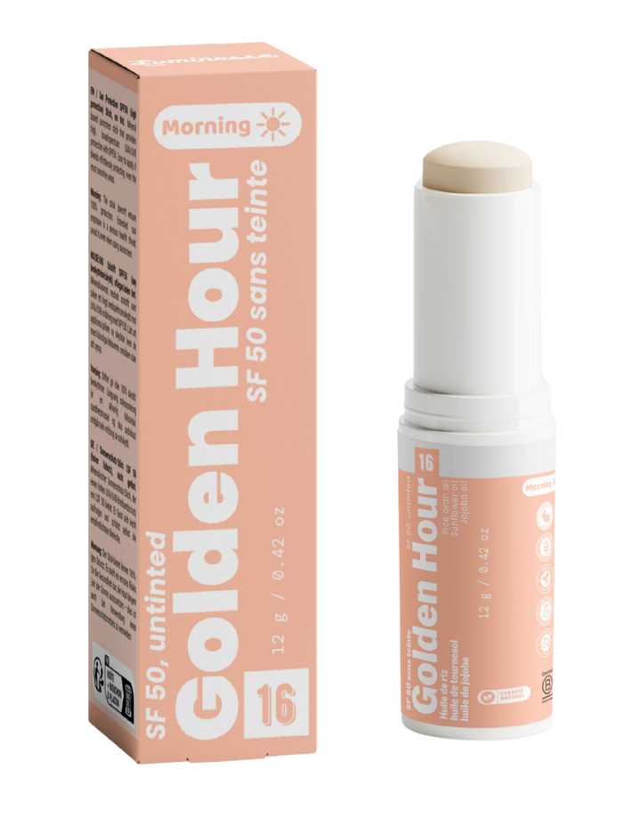 Packshot de Golden Hour n°16 de Luminesse Paris avec son étui pêche et son stick solaire SPF 50 sans teinte de 12 g. Le produit est présenté ouvert avec le stick beige visible, à côté de sa boîte ; la mention Morning et les huiles de riz, tournesol et jojoba figurent sur le packaging.