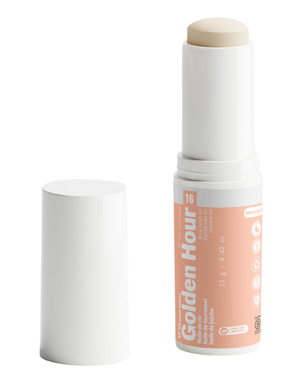 Packshot détouré de Golden Hour n°16 de Luminesse Paris, stick solaire SPF 50 de 12 g dans un tube blanc avec étiquette pêche. Le stick beige est sorti du tube et le capuchon blanc est posé à côté ; la mention Morning et les huiles de riz, tournesol et jojoba sont visibles sur le packaging.