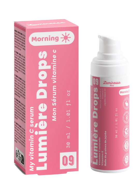 Packshot de Lumière Drops n°09 de Luminesse Paris avec son étui rose et son flacon pompe blanc de 30 ml. Le produit et la boîte sont présentés côte à côte sur fond transparent ; la mention Morning ainsi que les références à la vitamine C, vitamine E et huile de graines de jojoba sont visibles.