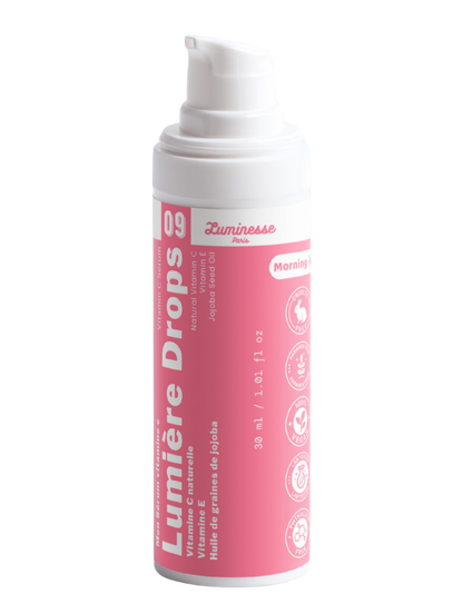 Packshot détouré de Lumière Drops n°09 de Luminesse Paris, sérum vitamine C en flacon pompe blanc de 30 ml avec étiquette rose. Le produit est présenté seul sur fond transparent ; les mentions vitamine C, vitamine E, huile de graines de jojoba et Morning sont visibles sur le packaging.